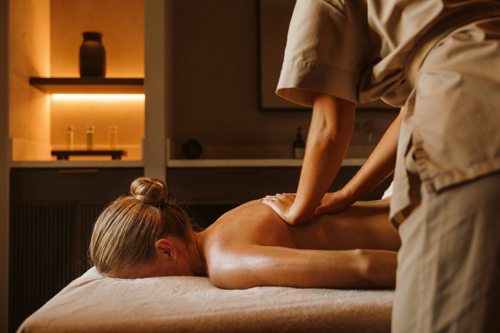 A therapist giving a back massage in a warmly lit treatment room