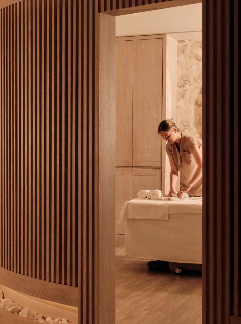 A therapist preparing a treatment room behind a slatted wooden screen